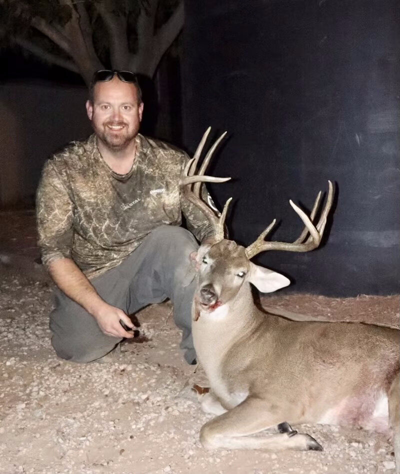 Mature whitetail buck against the oil tank under a clear Texas night
