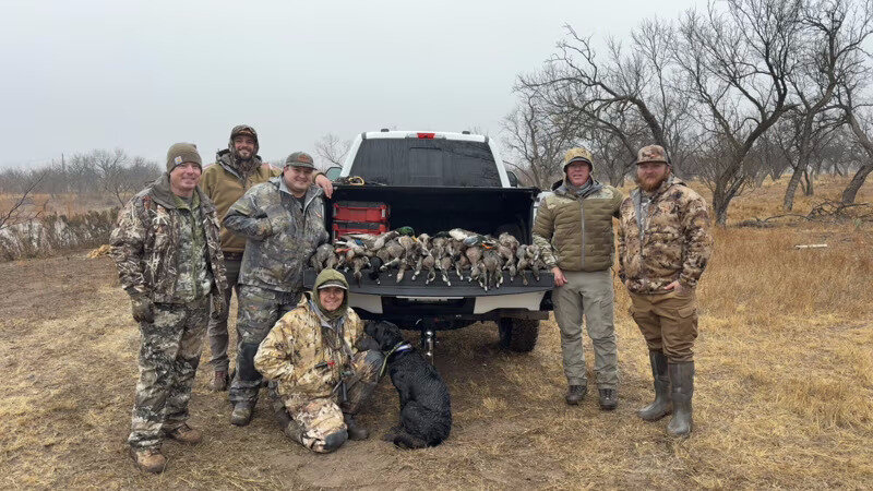 Hunters and retriever with a morning duck bag on the tailgate